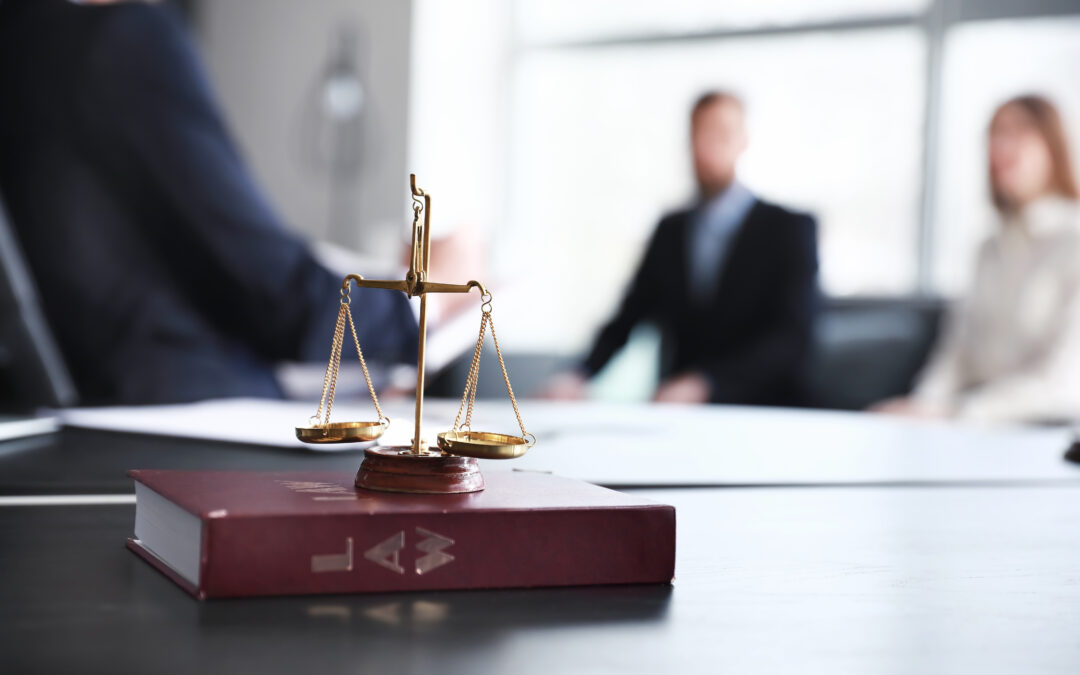 A couple talks to a lawyer in the background while the image focuses on a weighing scale.